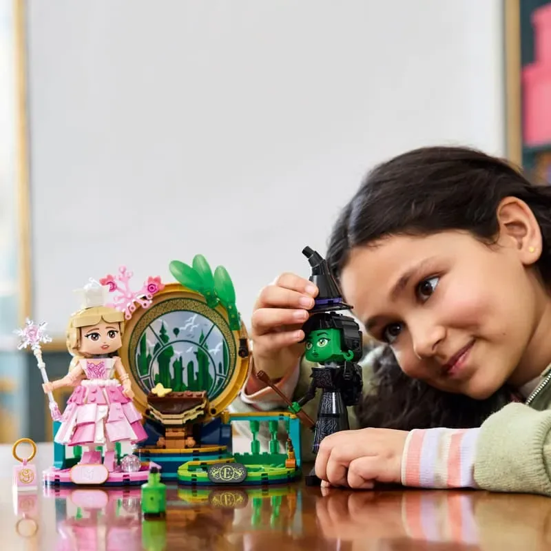Girl playing with Lego Elphaba & Glinda figures.