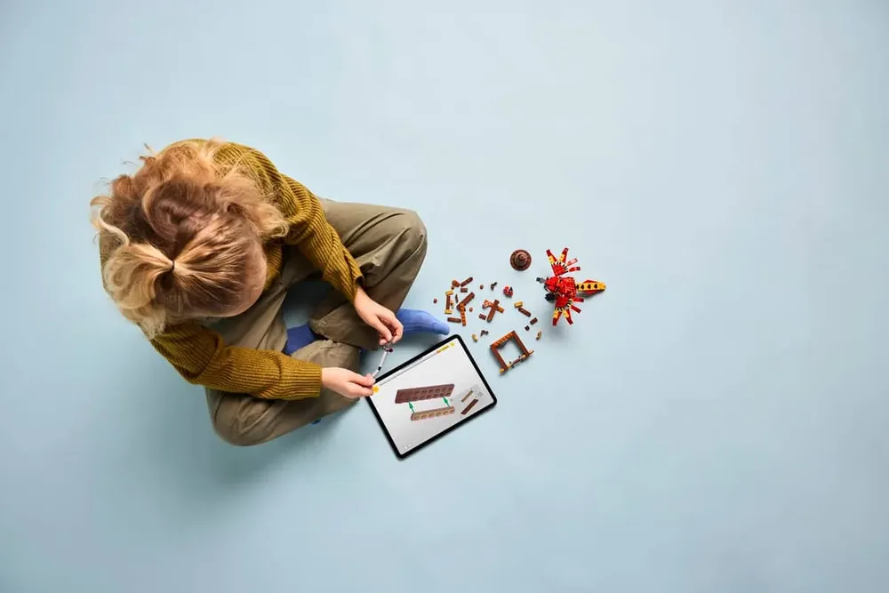 Overhead view of child building with digital instructions.