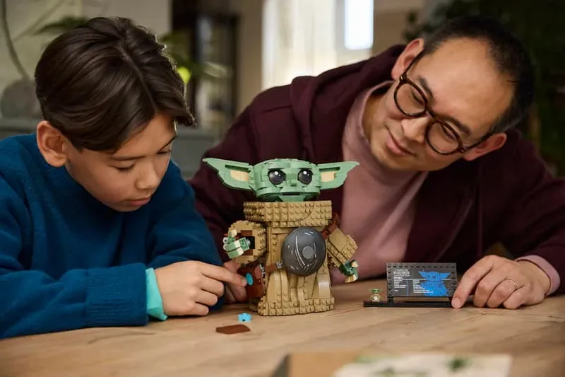 Child and adult building LEGO Grogu.