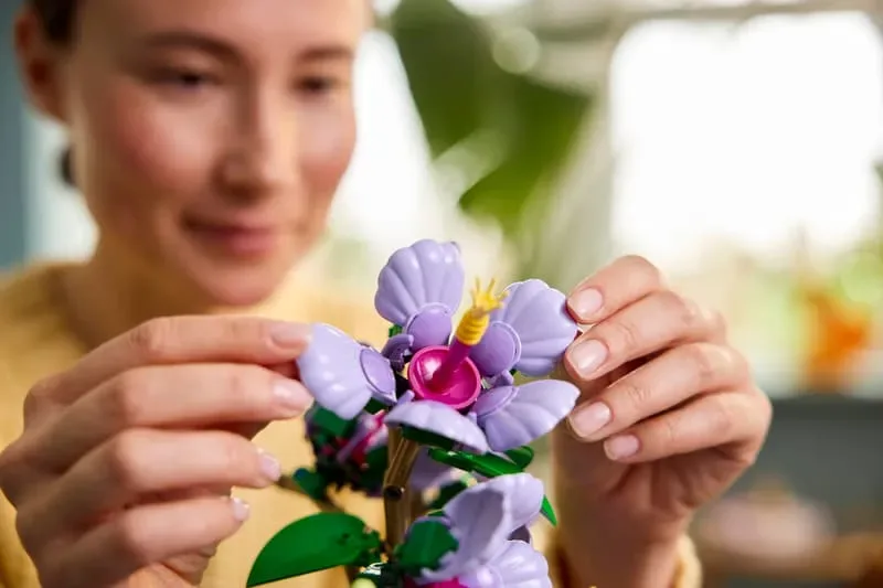 Hands adjusting Lego Hibiscus flower.