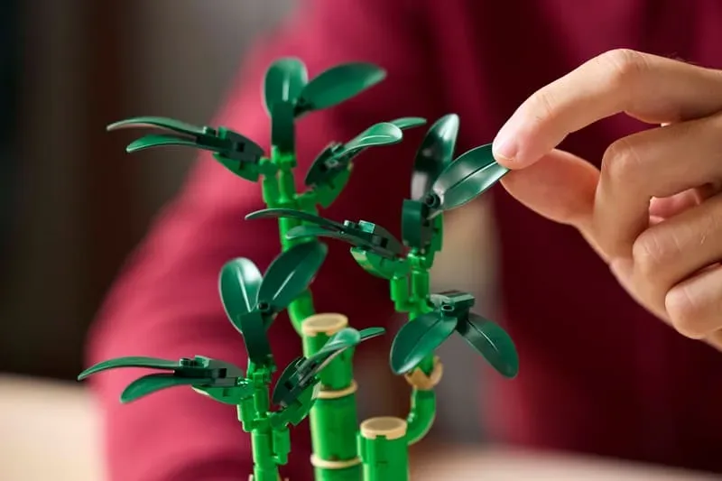 Hand adjusting LEGO bamboo leaves.