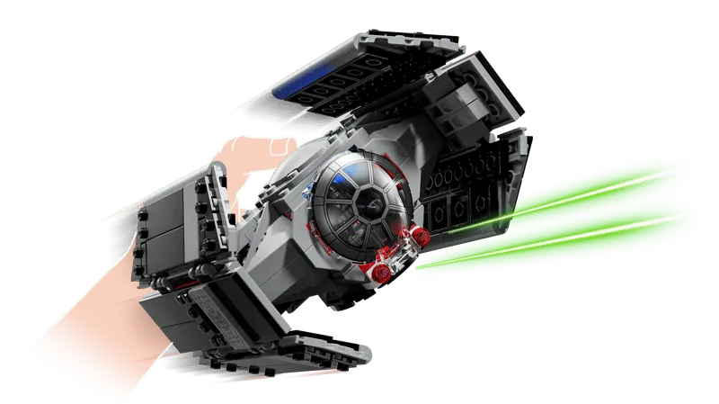 A hand holding Darth Vader's TIE Fighter, making it appear to fly and fire green lasers, demonstrating the active play element of the set.