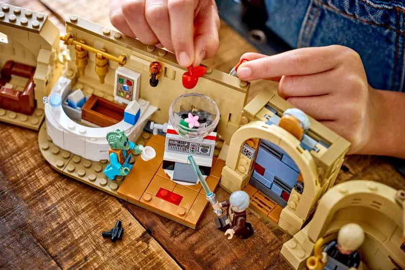 A child's hands playing with the central bar section of the Lego SMART Play Mos Eisley Cantina 75425, featuring Obi-Wan Kenobi and Greedo minifigures.