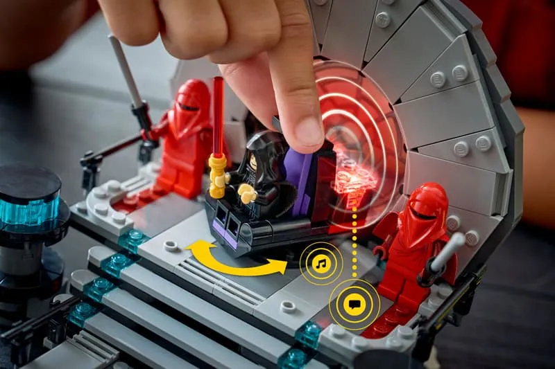 A hand interacting with Emperor Palpatine's throne in the LEGO Star Wars 75427 set, showing glowing red Smart Play indicators for sound and visual effects.