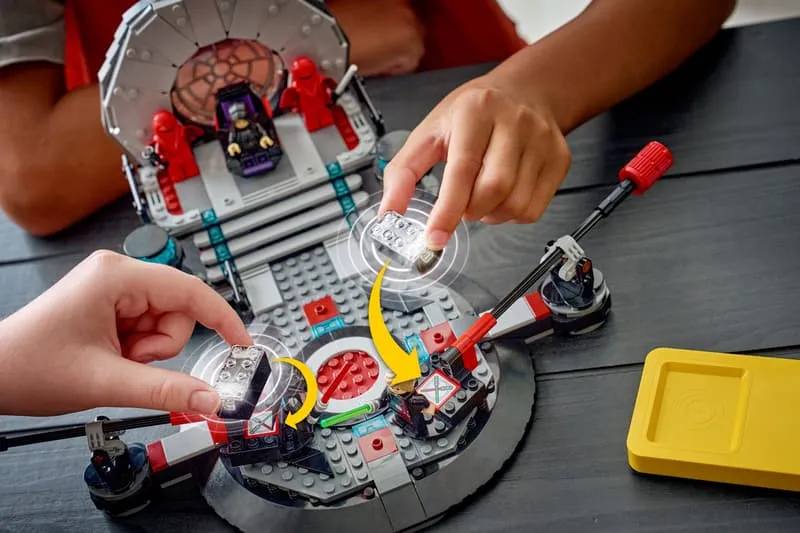 Two hands placing clear Smart Bricks into the interactive modules of the LEGO Star Wars 75427 Throne Room duel platform.