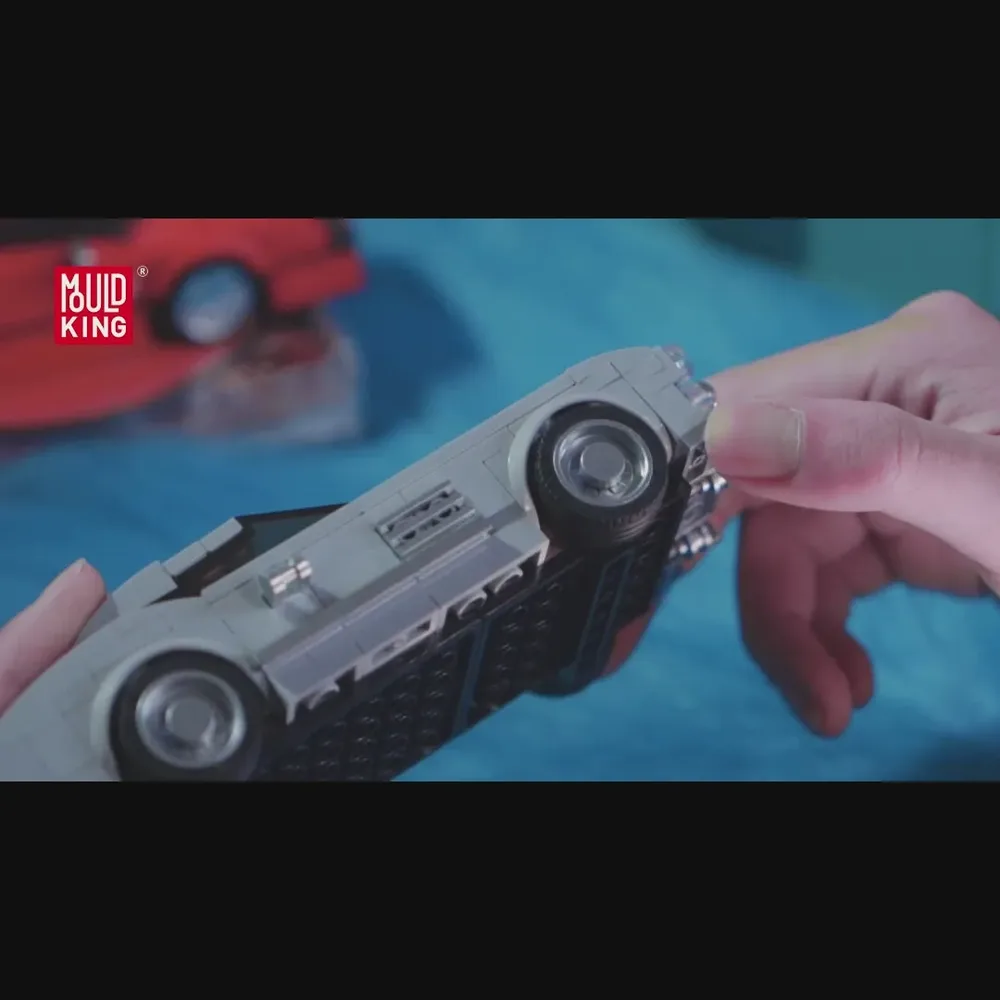Hand holding grey brick car model's underside.