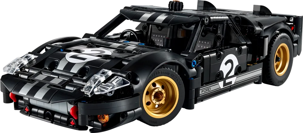 A black LEGO Technic 1966 Ford GT40 MKII race car model, with white racing stripes and the number 2 on the hood and side, displayed from a front three-quarter angle. It features gold wheels, clear headlights, and exposed Technic pins.