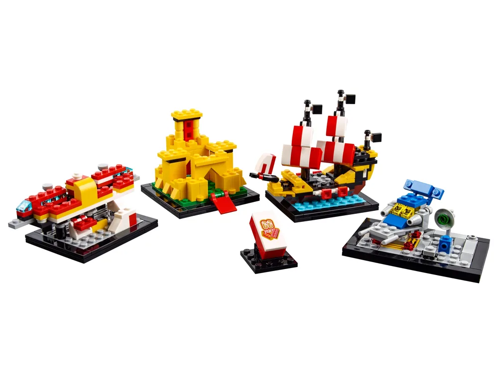 A white background displays four miniature LEGO builds: a yellow castle, a red and yellow train, a black and red pirate ship with striped sails, and a grey and blue space cruiser, alongside a small red and white "60 years" tile.