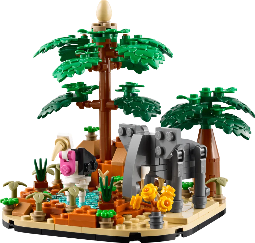 A LEGO African Savanna Diorama featuring a grey elephant, a black and white bird, a watering hole with blue trans-clear bricks, and two large palm trees on a tan and brown base.