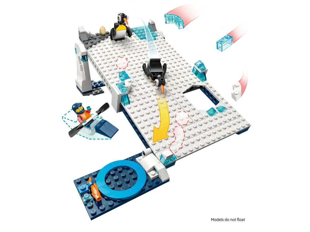 An overhead shot of a white and blue LEGO ice slide with two black and white LEGO penguins, one sliding down an incline. A LEGO minifigure in a blue boat with an oar waits at the bottom of the slide.