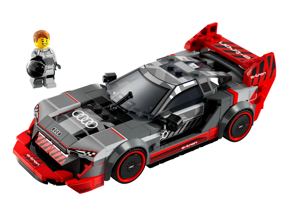 The LEGO Speed Champions Audi S1 e-tron quattro Race Car set 76921 is displayed on a white background, featuring a dark grey and red car with a minifigure in a white racing suit holding a black helmet. The car shows detailed stickers and an aggressive front spoiler.