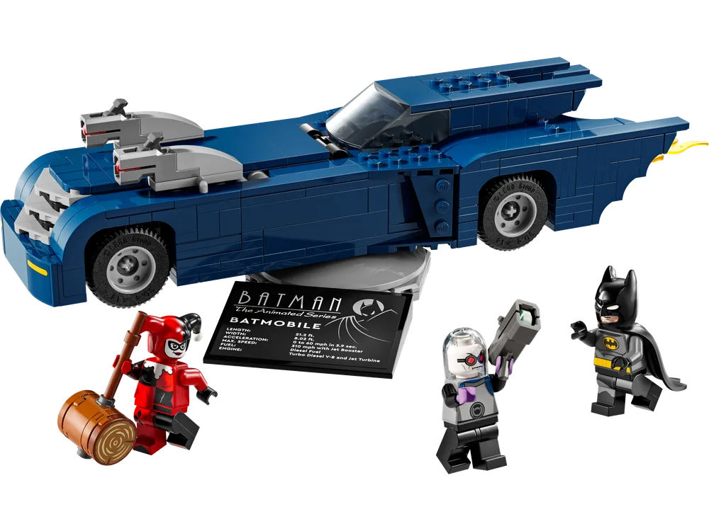 The complete LEGO DC Batman Batmobile (76274) model with its sleek dark blue design, showcasing its long profile, visible stud shooters, and trans-clear canopy. Batman, Harley Quinn with a mallet, and Mr. Freeze with his ice gun stand alongside a display plaque detailing the Batmobile's specs.