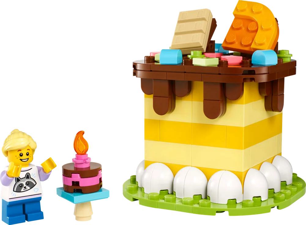 A LEGO birthday cake build with yellow and white layers, brown frosting, colorful sprinkles, a tan chocolate bar, and an orange cheese wedge on top, next to a minifigure and a tiny birthday candle.