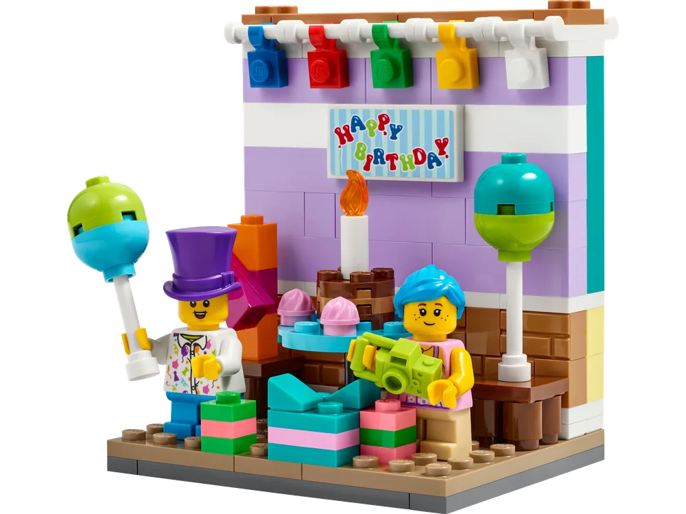 A LEGO Birthday Diorama, set 40584, showcasing two minifigures, presents, balloons, and a 'Happy Birthday' sign against a colorful wall backdrop.