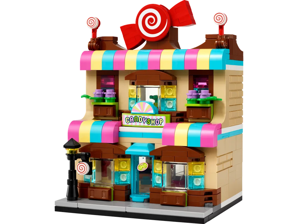 Front view of a vibrant two-story LEGO candy shop with striped awnings, a large red candy bow, and lollipop decorations.