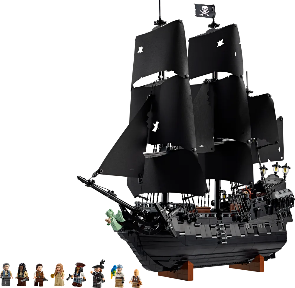 A LEGO Icons model of the Black Pearl pirate ship, featuring black sails with holes, a dark hull, and eight minifigures standing in a line in front of the ship.