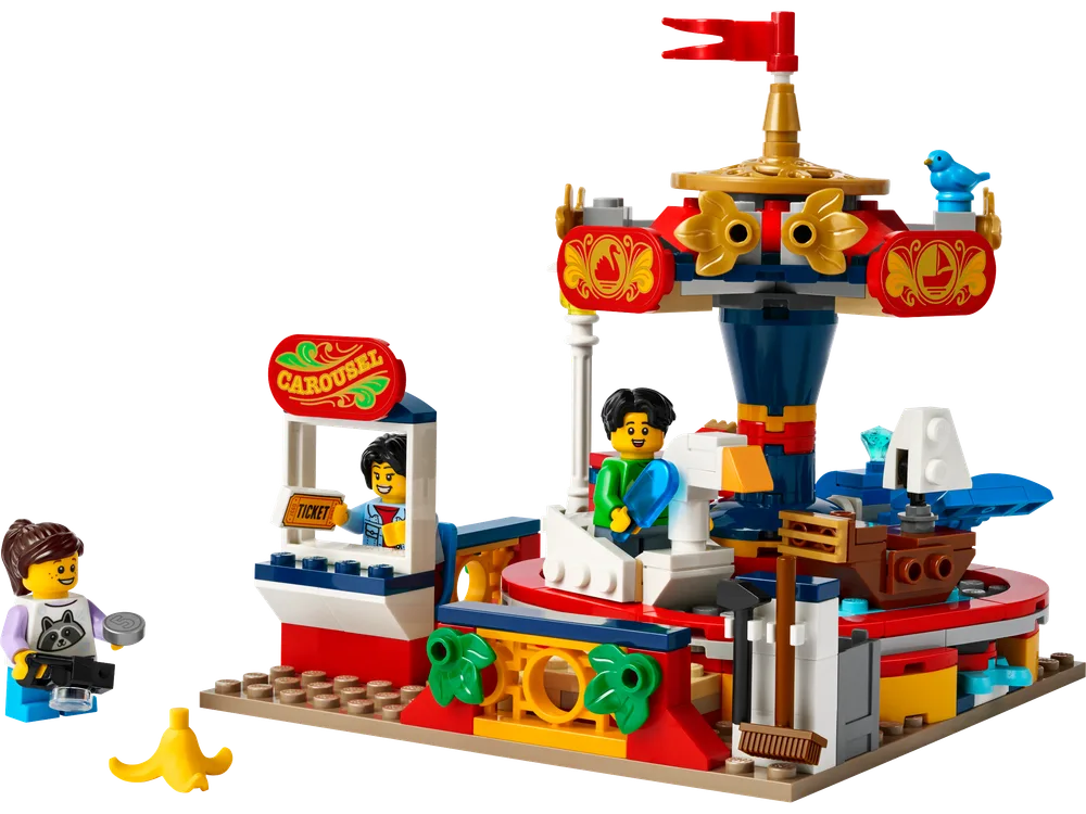 A bright red and gold LEGO carousel with two minifigures, a ticket booth, and a banana peel on a tan baseplate.