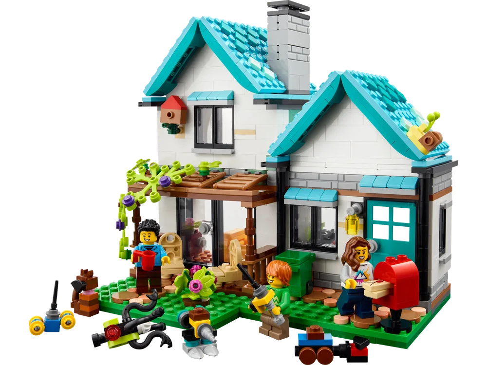 Full exterior view of the LEGO Creator 31139 Cozy House, showcasing a family engaging in outdoor activities like watering plants and checking the mailbox. The house features a teal roof, white walls, and a welcoming porch.
