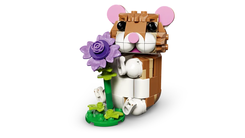 A LEGO-built brown and white hamster sitting upright, holding a purple flower. It has pink ears and a pink nose, with black eyes.