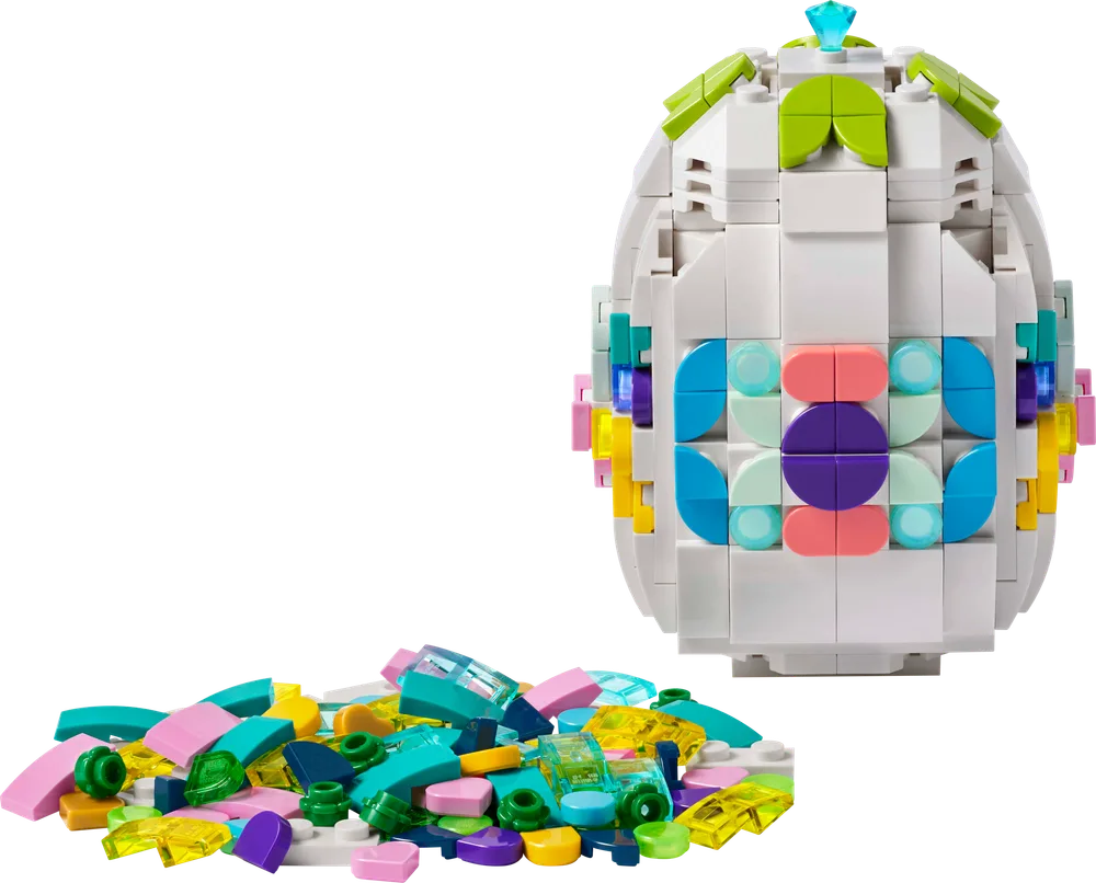 A LEGO decorative Easter egg, primarily white, adorned with colorful patterns using various pastel and trans-clear LEGO pieces scattered in a pile on the left.