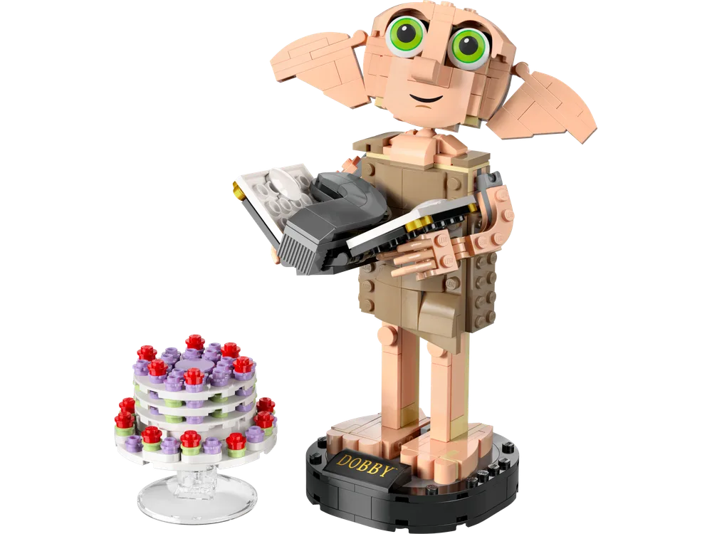A brick-built Dobby figure stands on a black display base, holding Tom Riddle's diary and a grey sock. Beside him is a layered birthday cake on a clear stand.