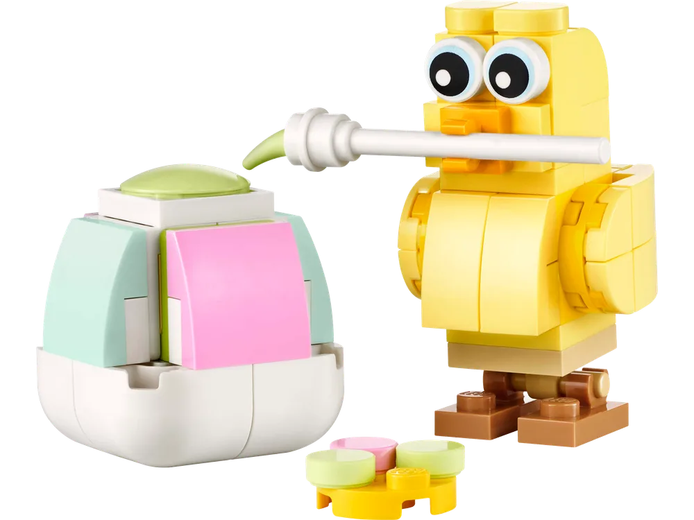 A yellow LEGO brick chick holds a paintbrush, adding green paint to a pastel-colored Easter egg build. A small paint palette sits nearby.