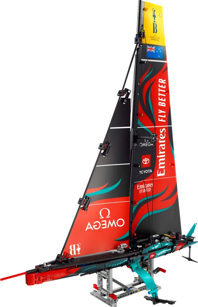 A full, angled view of the LEGO Technic Emirates Team New Zealand AC75 Yacht on its display stand, showcasing its black and red sails with teal accents.