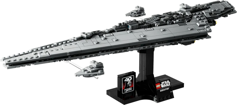 The LEGO Star Wars Executor Super Star Destroyer set 75356 is displayed on its black stand against a plain white background. The long, triangular ship is light gray, with darker gray greebling along its spine and an imperial red engine glow. Two smaller, micro-scale Star Destroyers float alongside, attached by clear rods. The display stand features a '40 Return of the Jedi' anniversary logo and the set name.