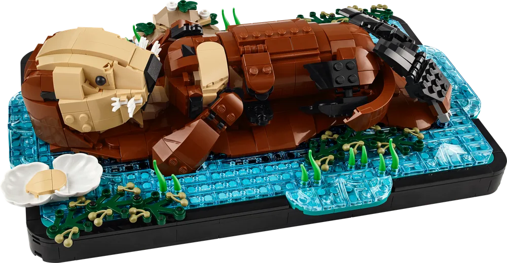 LEGO Ideas 21366 Floating Sea Otters set featuring a large brick-built otter on its back in trans-blue water, holding a clam, with seaweed details on a black base.