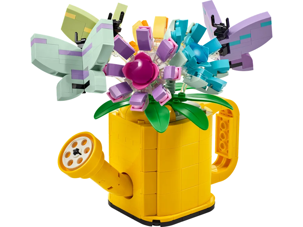 A bright yellow LEGO watering can filled with colorful LEGO flowers and two pastel butterflies, against a white background.