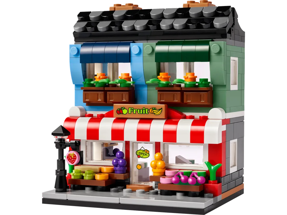 Front view of the LEGO 40684 Fruit Store set, showcasing the detailed facade with a red and white striped awning over the ground floor and blue and green awnings over the upper floor windows.