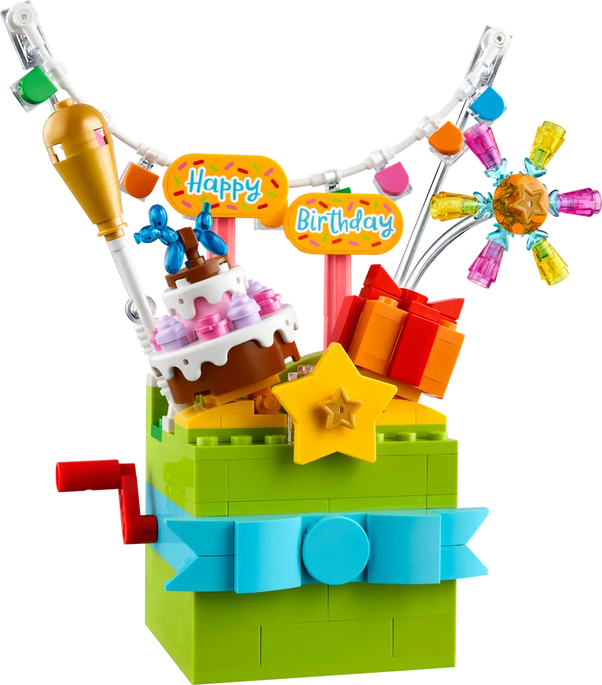 A close-up of the LEGO Birthday Gift Box pop-up model, showcasing the cake, presents, and 'Happy Birthday' banner emerging from a green box with a blue ribbon.