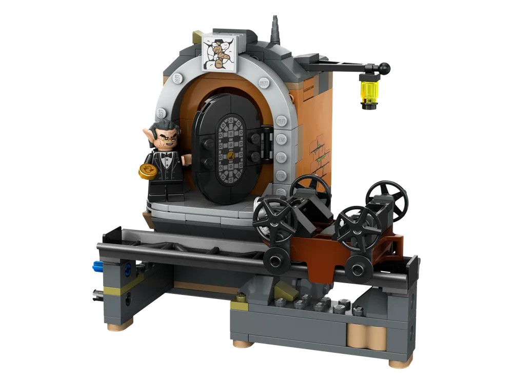 Front view of the Gringotts™ Vault model with a goblin minifigure holding a gold coin, next to a black vault door and a mine cart mechanism.