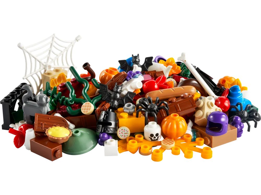 A scattered pile of Halloween-themed LEGO bricks and elements, including pumpkins, bats, spiders, bones, food items like pie and bread, a white spiderweb, and various colored plates and bricks.
