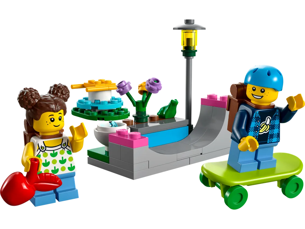Two LEGO City minifigures, a girl with brown pigtails holding a red heart and a boy on a skateboard, stand next to a small park build featuring a gray skate ramp, lamppost, and spinning water feature.