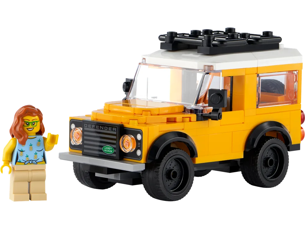 A yellow LEGO Land Rover Classic Defender next to a smiling minifigure.