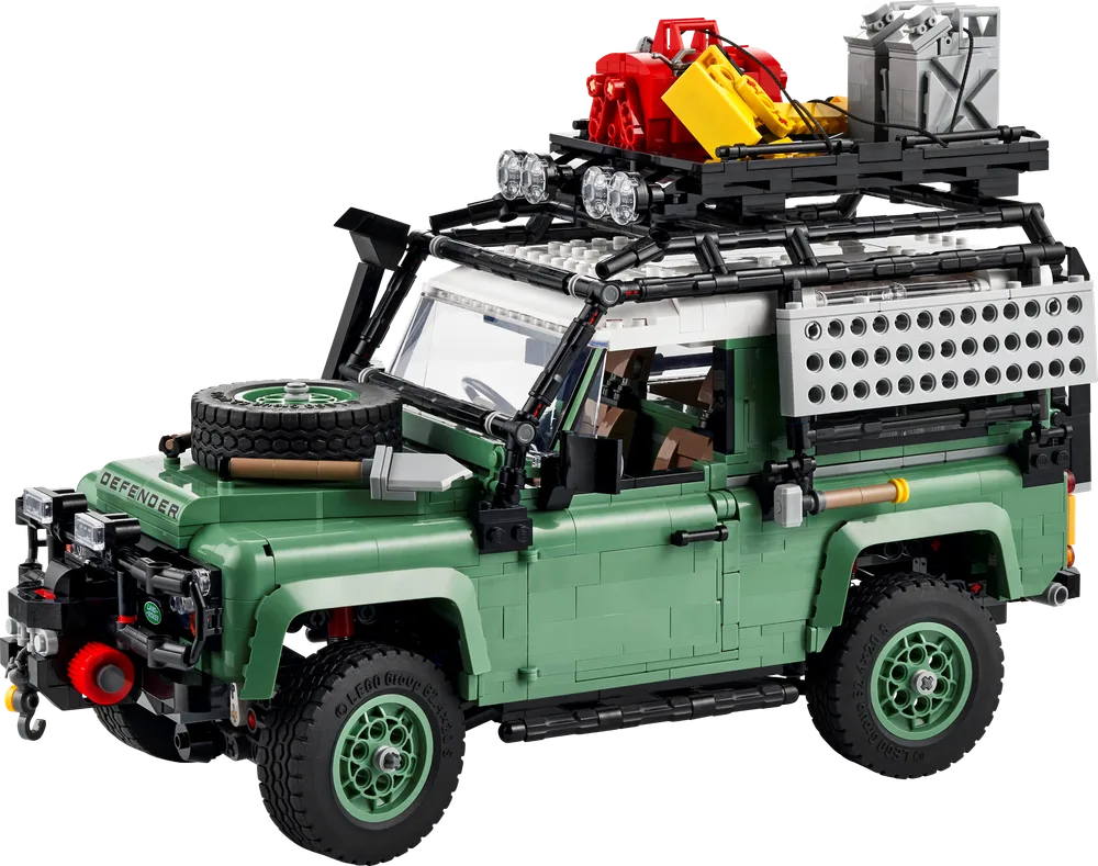 Full view of the LEGO Land Rover Classic Defender 90 in expedition configuration, dark green with a white roof, roof rack, front winch, side storage boxes, and other off-road accessories, angled front-right.
