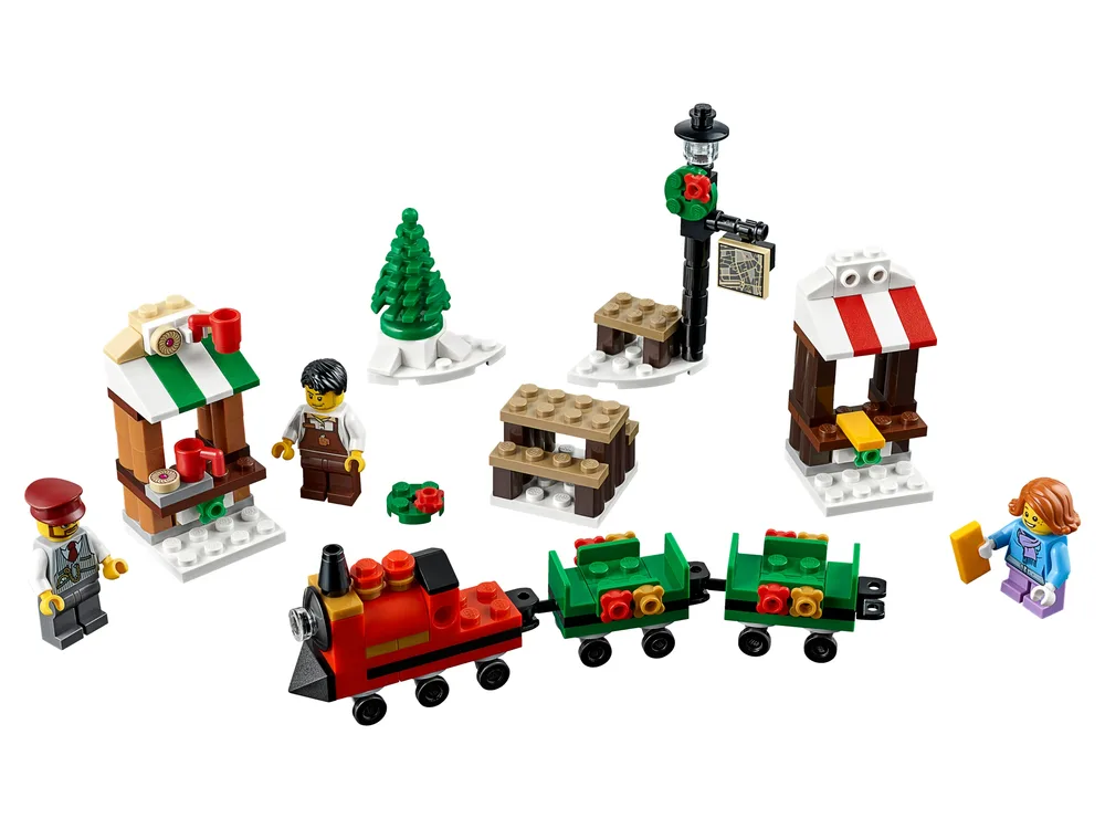 An overhead view of the complete LEGO Christmas Train Ride set, featuring a red train, two green wagons, two market stalls, a lamppost, a bench, a Christmas tree, and three minifigures.