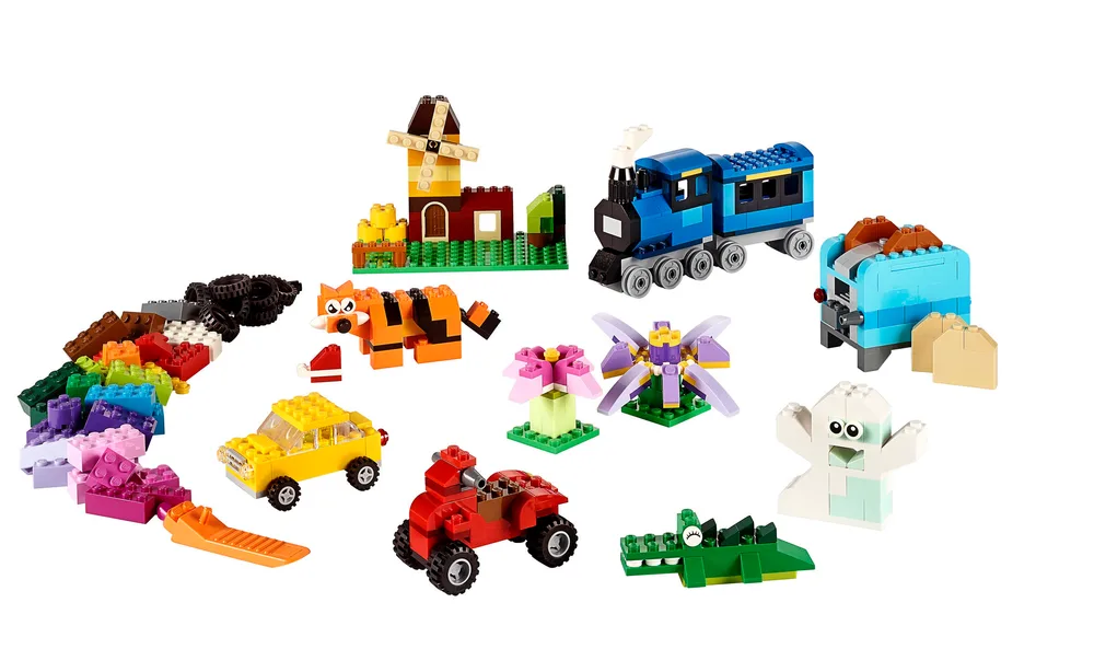 A collection of colorful LEGO models and loose bricks including a train, car, tiger, crocodile, and flowers, all built from the LEGO Classic Medium Creative Brick Box 10696.