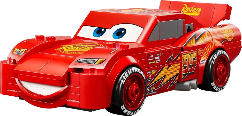 A front-quarter view of the LEGO Speed Champions Lightning McQueen car model, showcasing its red body, large printed eyes, and Rusteze decals.