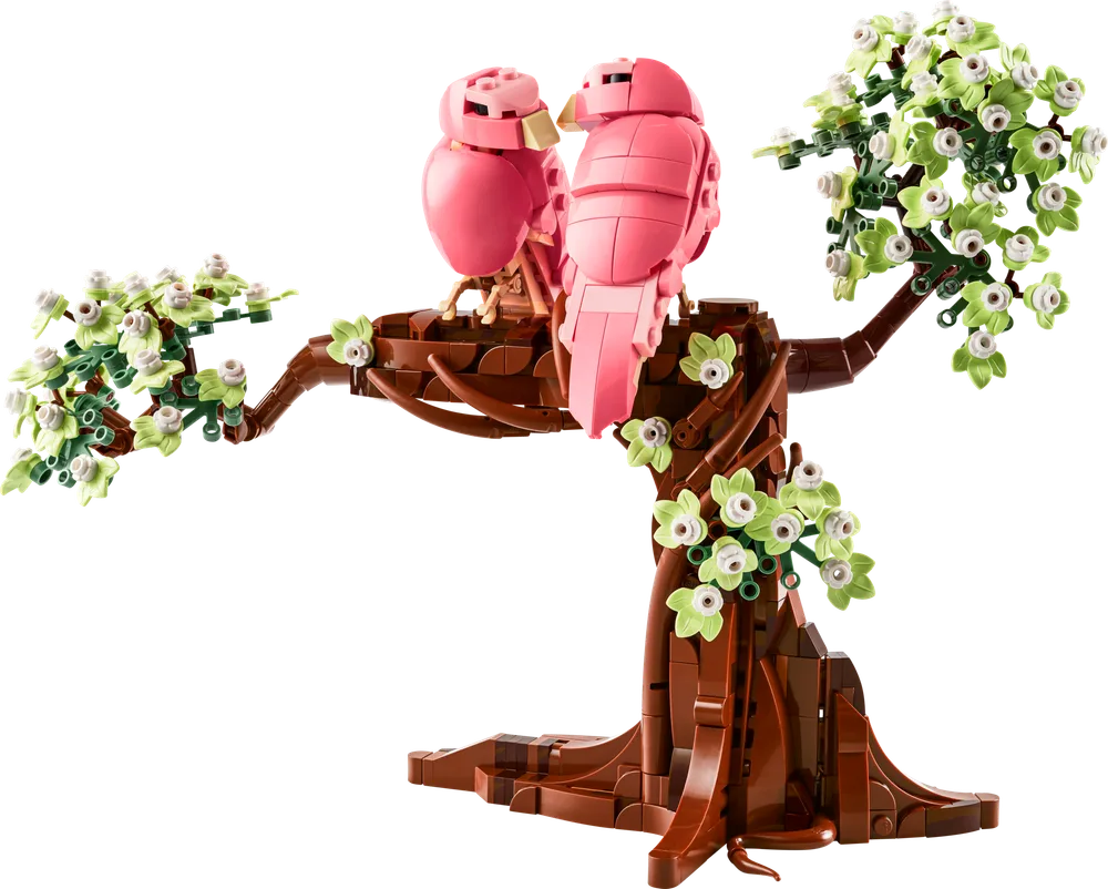 A pair of pink love birds with light green leaves perched on a brown tree trunk, white background.