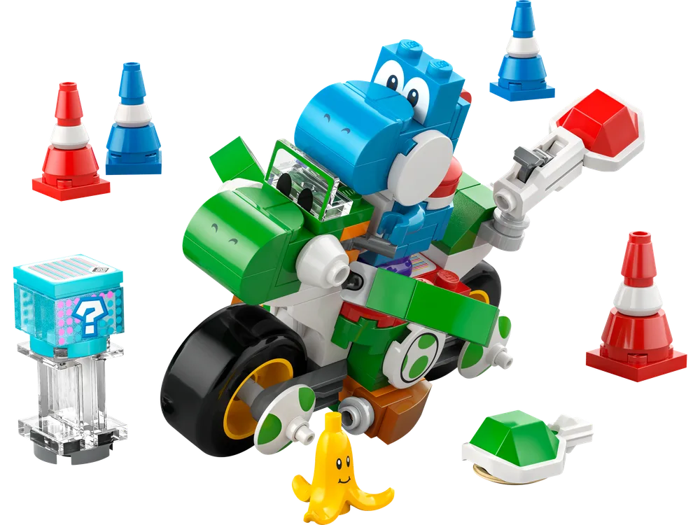 A dynamic overhead shot of the LEGO® Super Mario™ Yoshi's Mini Bike set, featuring Blue Yoshi on his green bike, surrounded by a question mark item box, a banana peel, a green shell, and red and blue traffic cones against a white background.