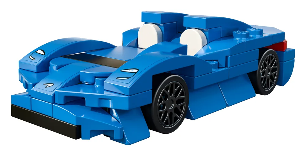 A close-up, eye-level view of the LEGO McLaren Elva set in vibrant blue, showcasing its aerodynamic design, black wheels, and white cockpit seats against a white background.