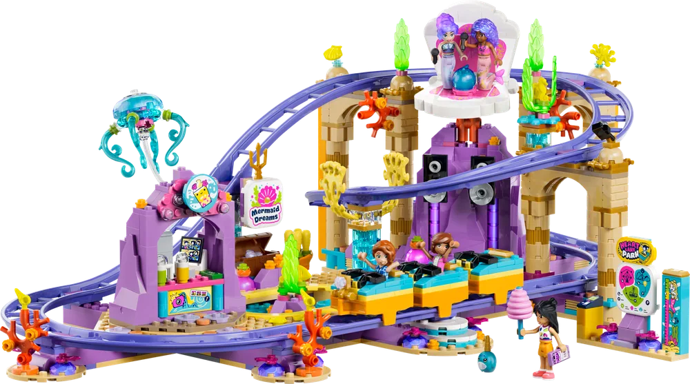 A wide view of the LEGO Friends 42703 Mermaid Roller Coaster set, featuring purple tracks, an elaborate rock structure, a shell stage, and several minifigures on the ride. A glowing jellyfish is on the left.