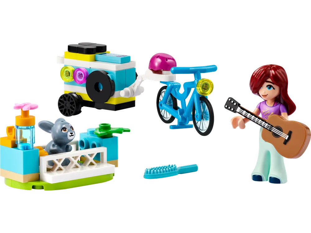 A LEGO Friends minifigure named Autumn with red hair holds an acoustic guitar. To her left are three small builds: a teal and yellow mobile music trailer, a blue bicycle with a pink helmet, and a small habitat with a grey bunny, along with a teal brush.