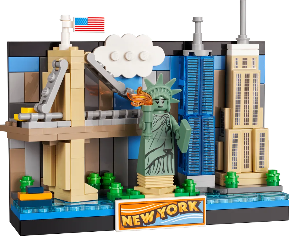 A LEGO Creator New York Postcard set (40519) prominently features the Statue of Liberty, Brooklyn Bridge, One World Trade Center, and Empire State Building against a blue sky, all mounted on a dark base with a 'NEW YORK' tile.