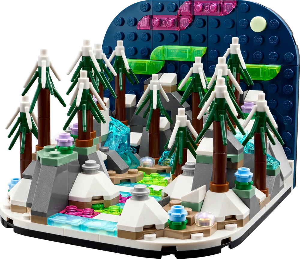 A detailed LEGO diorama showcasing a snowy, mountainous landscape under a dark blue sky with vibrant green and pink Northern Lights and a bright moon.