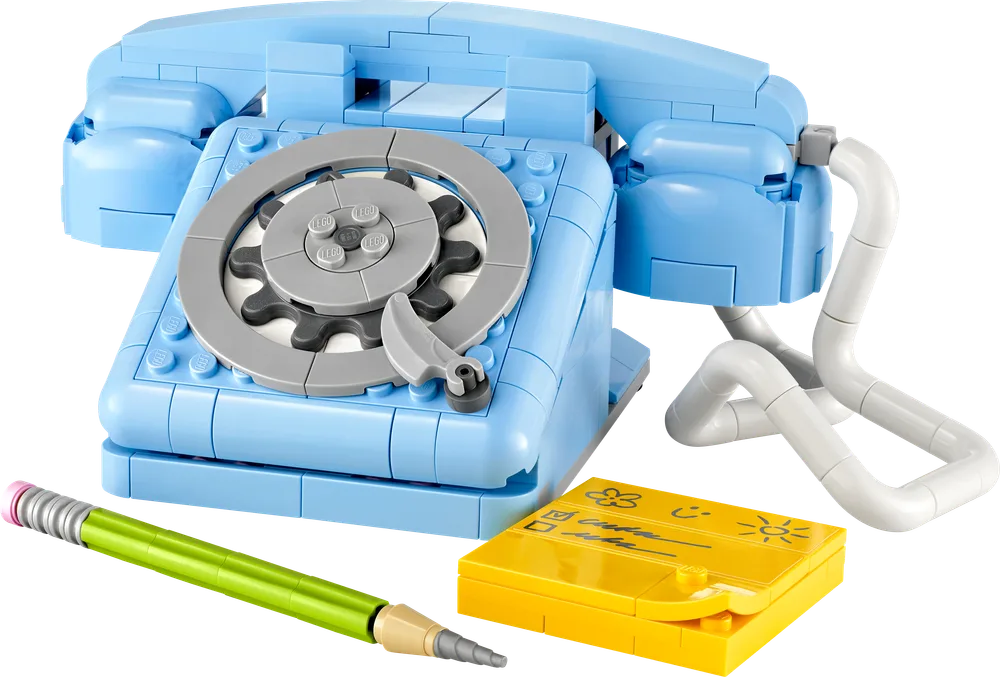 Close-up view of the light blue retro telephone with a rotary dial, accompanied by a green pencil and yellow notepads.