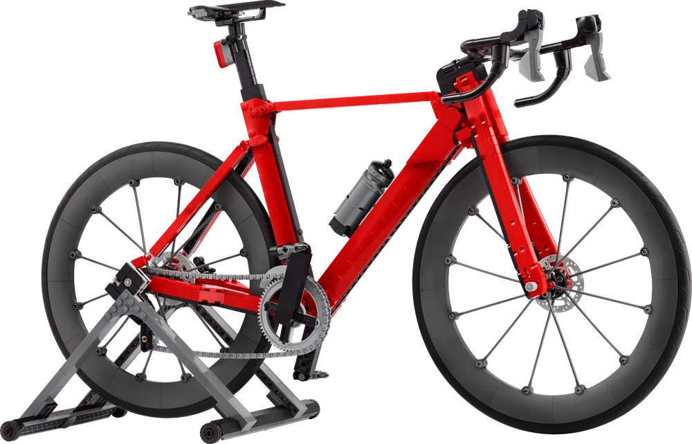 A detailed red LEGO road bike model on a grey training stand against a white background.