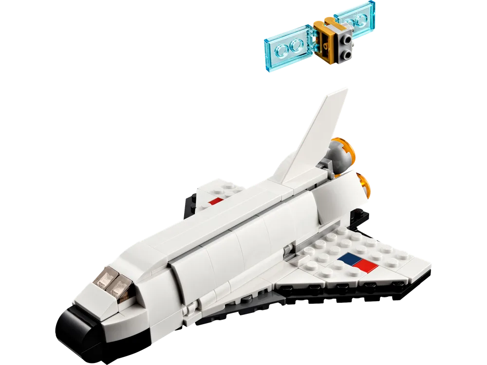A white LEGO space shuttle model with black accents and small red and blue square details on its wings. A small, separate LEGO satellite with clear blue panels is floating above it.